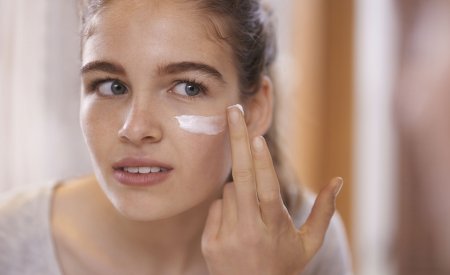 Teenage girl applying moisturizer