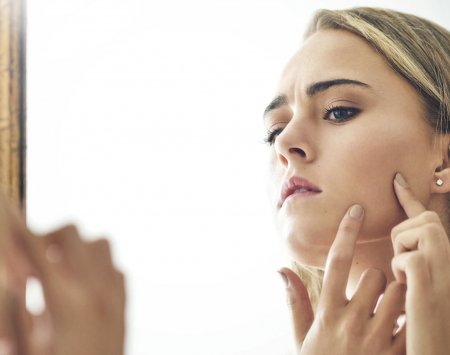 teenager examines her skin